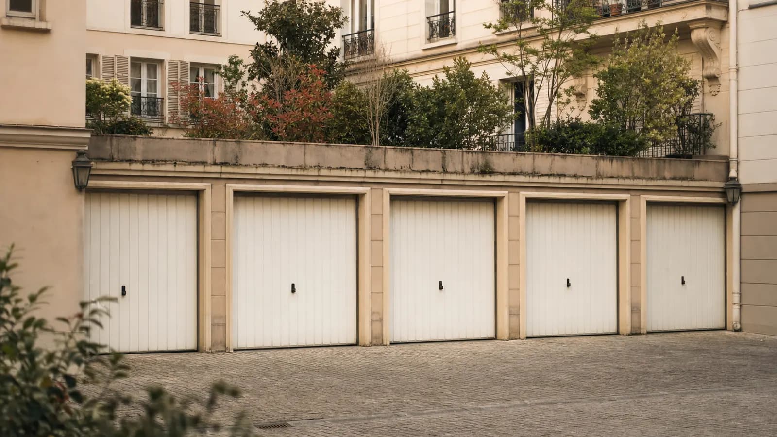 Rangée de portes de garage fermées dans une cour d'immeuble.